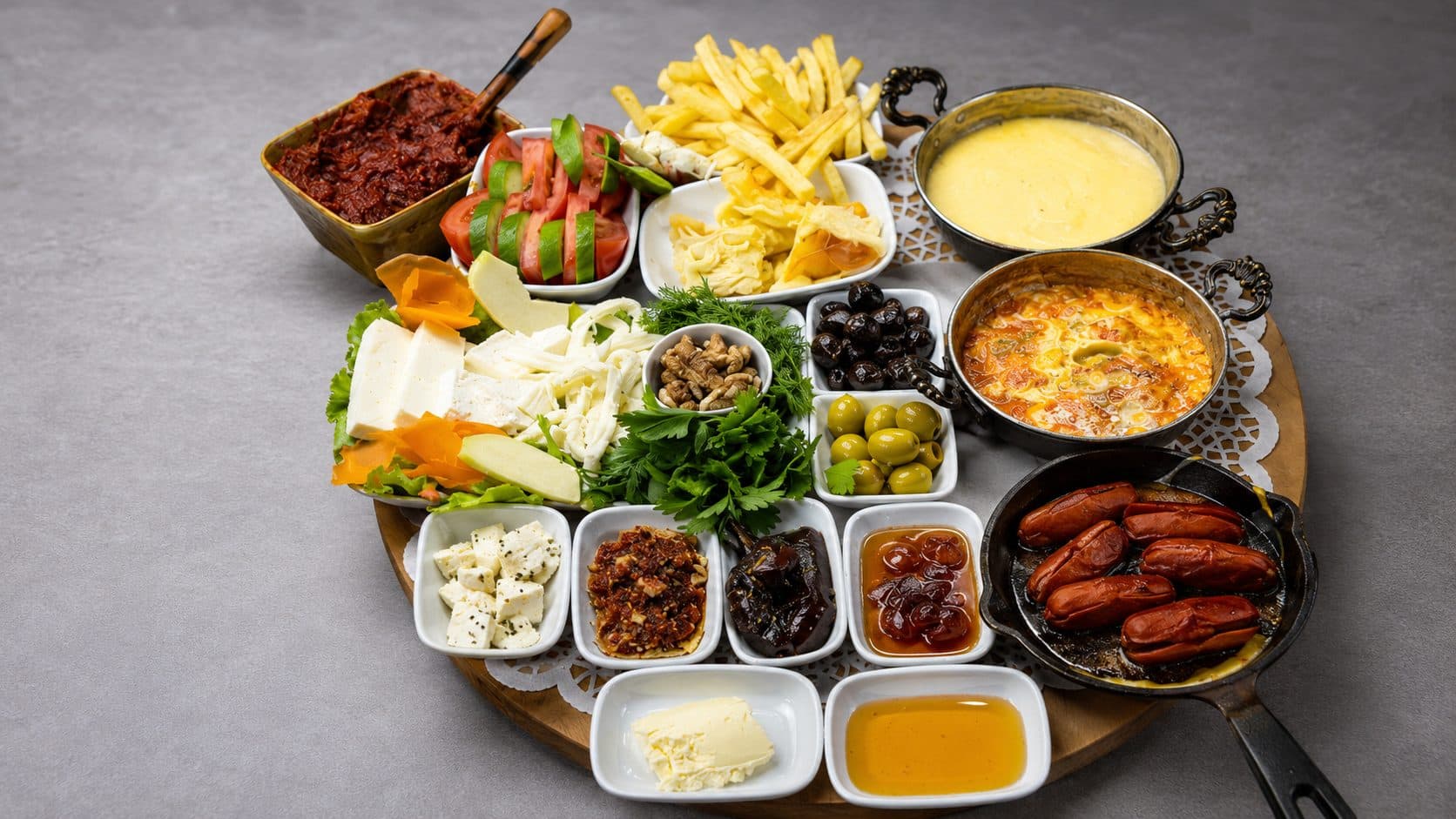 Ahşap tepside serpme kahvaltı: kuymak, menemen, tavada sucuk, peynir çeşitleri, zeytin ve el yapımı reçeller. Kibaroğlu UNDAN Nimetler, İzmit